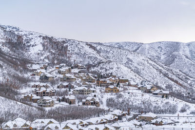 Snow covered houses by mountain against sky