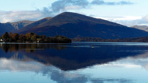 Scenic view of lake by mountains against sky