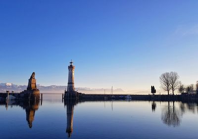 Reflection of building in lake against clear blue sky