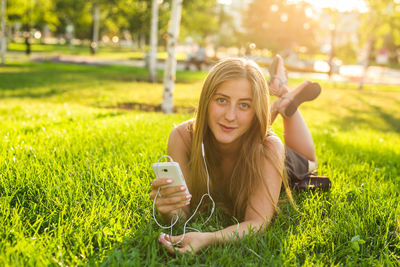 Portrait of smiling young man using mobile phone in grass