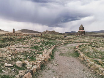 Dirt road amidst buildings against sky