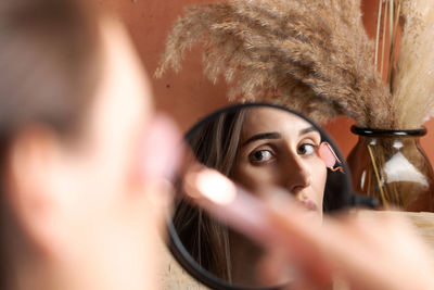 A beautiful brunette girl in the reflection of a mirror does a facial massage using a quartz massage 