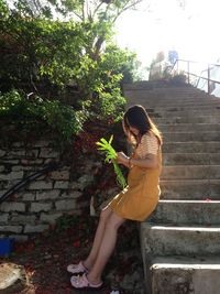 Side view of woman sitting on staircase