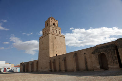 Low angle view of great mosque of kairouan against cloudy sky