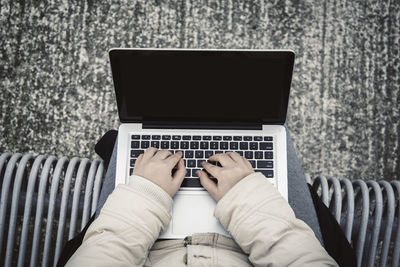 Midsection of woman using laptop on bench