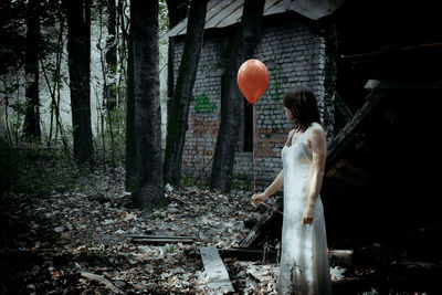 Rear view of woman with balloon balloons against trees