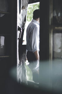 Rear view of boy working at window