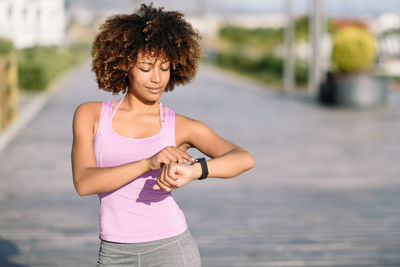 Woman using smart watch while standing on footpath