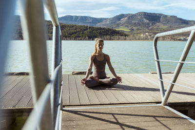 Young woman meditating on jetty