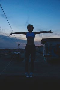 Rear view of man with arms outstretched standing against sky