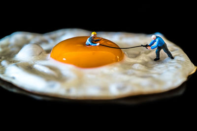 Close-up of figurines pulling string on omelet