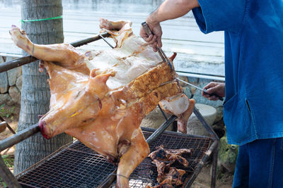 Midsection of man cutting grilled pork