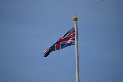 Low angle view of british flag waving against blue sky