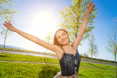 Young woman standing on field against sky during sunset