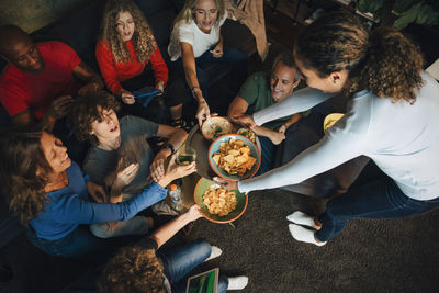 High angle view of smiling teenager giving nacho chips to family during sporting event