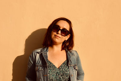 Portrait of young woman standing against yellow wall