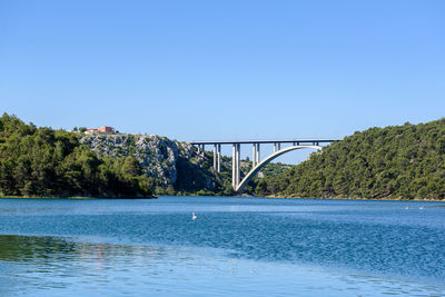 Bridge over river against clear blue sky