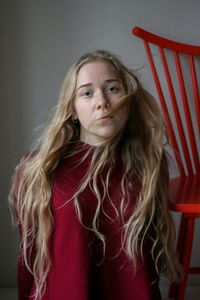 Portrait of beautiful young woman standing against wall