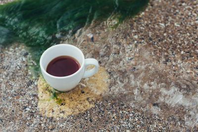 High angle view of black coffee in cup on rock