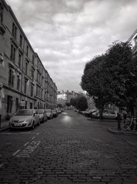 Cars on street in city against sky