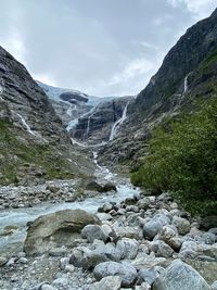 Scenic view of stream flowing through rocks against sky