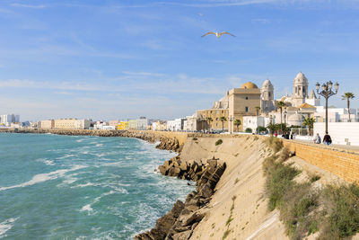 Buildings by sea against sky