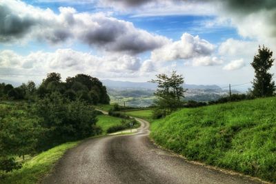 Country road against cloudy sky