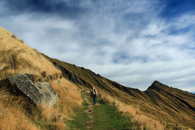 Rear view of woman walking on mountain against sky