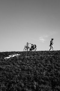 People riding bicycle on field against clear sky