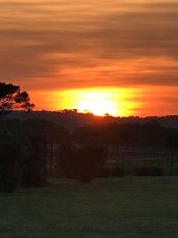 Scenic view of silhouette field against orange sky