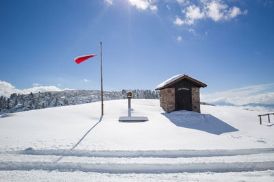 Flag on snow covered landscape against sky