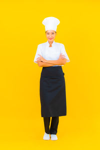 Portrait of woman standing against yellow background