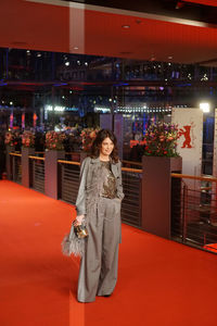 Portrait of woman standing against illuminated building at night