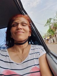 Portrait of young woman sitting on window