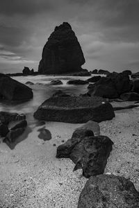 Rock formation on beach against sky