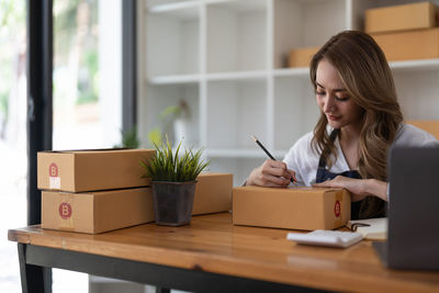 Young woman using laptop while sitting on table