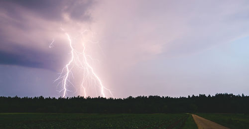 Scenic view of lightning over field against sky