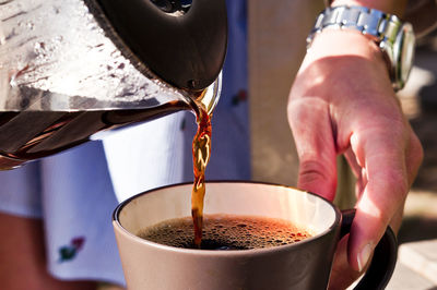 Midsection of man pouring coffee into cup