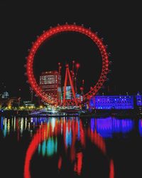 Reflection of illuminated ferris wheel in water at night