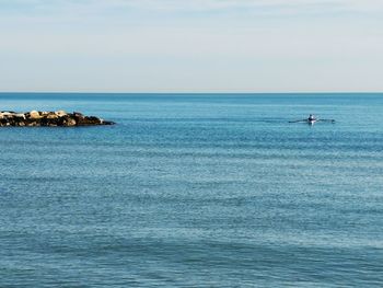 Scenic view of blue sea against sky. men canoeing in te calm sea. 