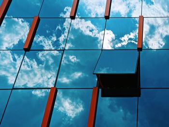 Low angle view of glass building against cloudy sky