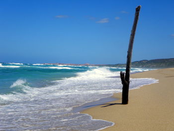 Wooden post at beach against sky