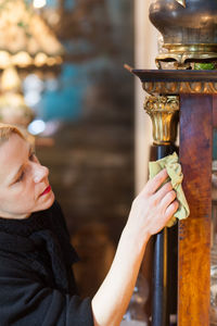 Close-up of mature woman cleaning furniture with fabric