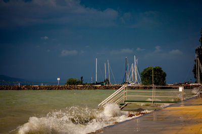 Sailboat on pier over sea against sky