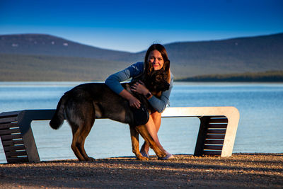 Portrait of woman sitting on shore against sky