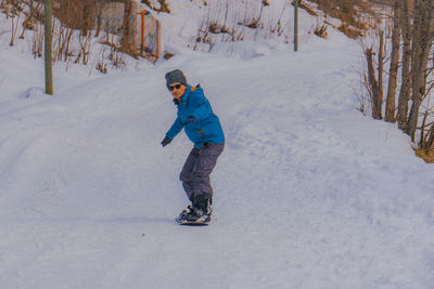 Full length of man snowboarding on snow covered land