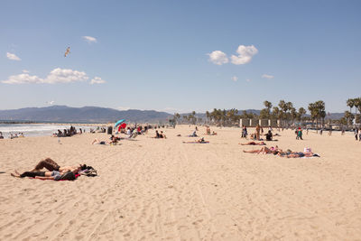 People relaxing on beach against sky