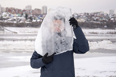 Man holding umbrella standing in city during winter