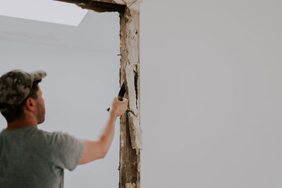 A man working with a crowbar in a doorway.