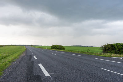 Road amidst field against sky